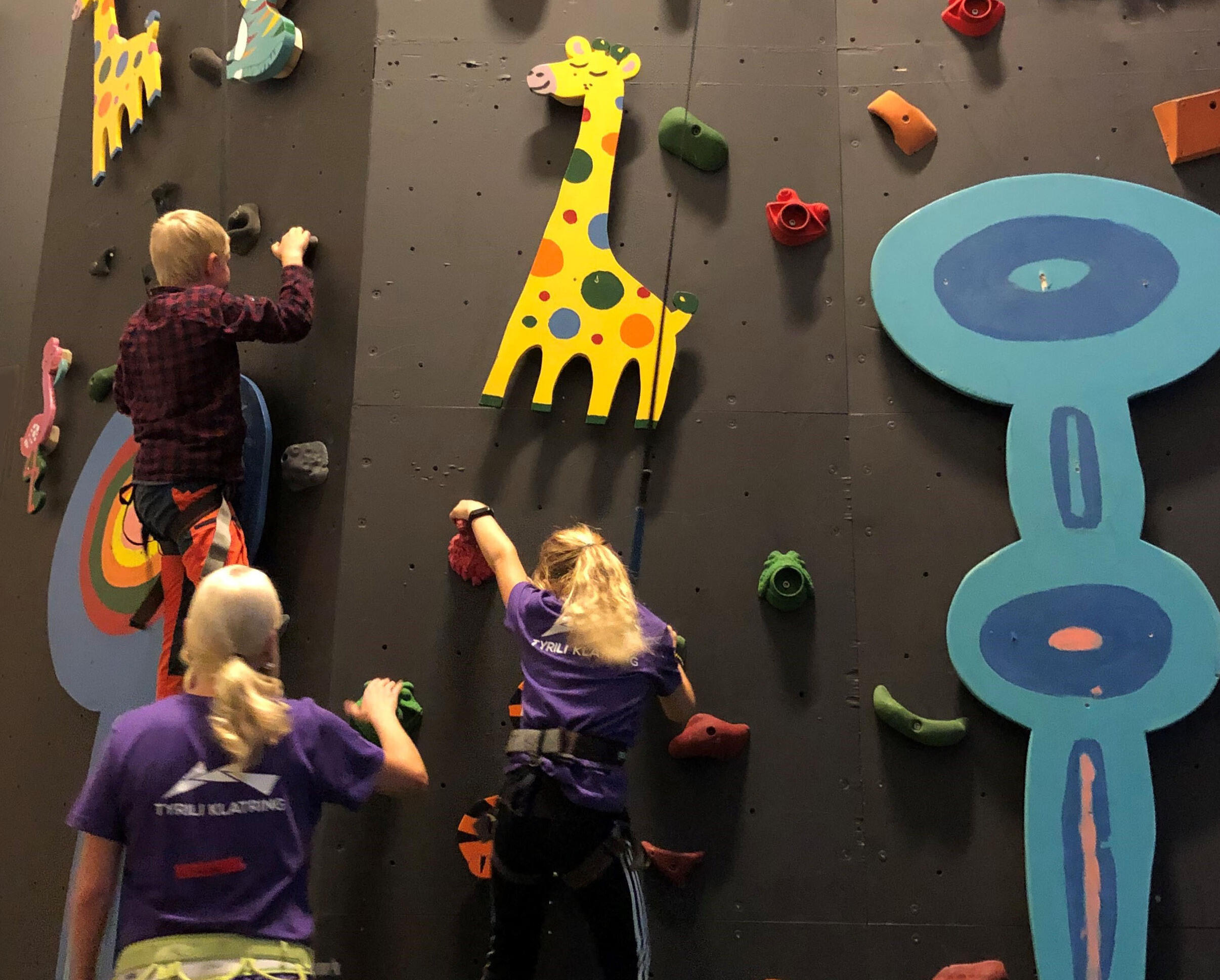 Barn som klatrer i vegg med fargerike figurer
